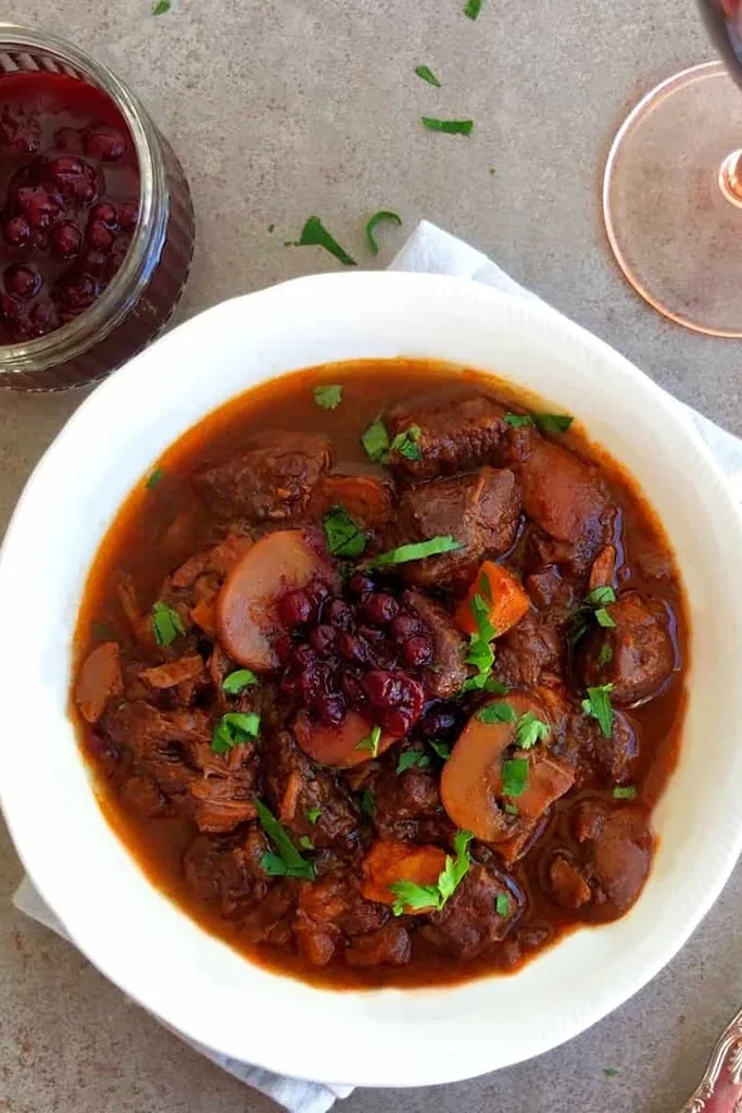 German venison goulash with cilantro on top in white bowl 