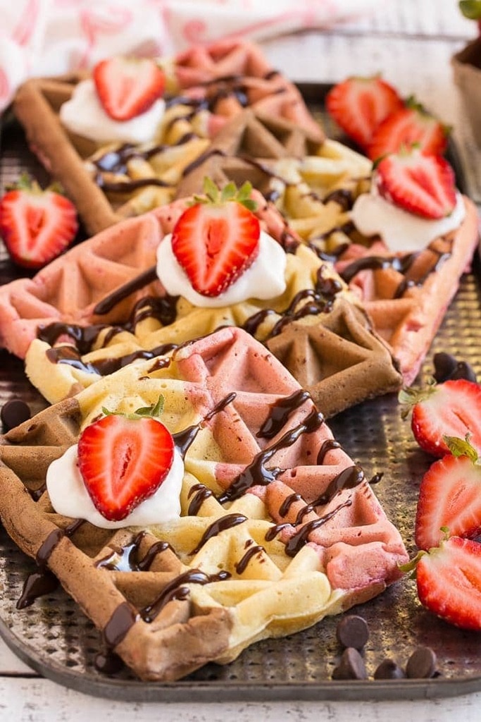 25 Valentine’s Day Breakfast Ideas For Kids 2 pink brown and white waffles with chocolate drizzle and strawberries