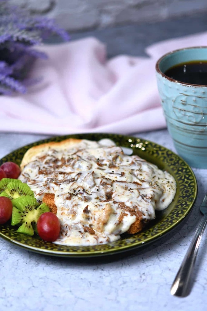 25 Venison Recipes You Will Love 15 deer meat venison with gravy on top with a side of grapes and kiwi on green plate