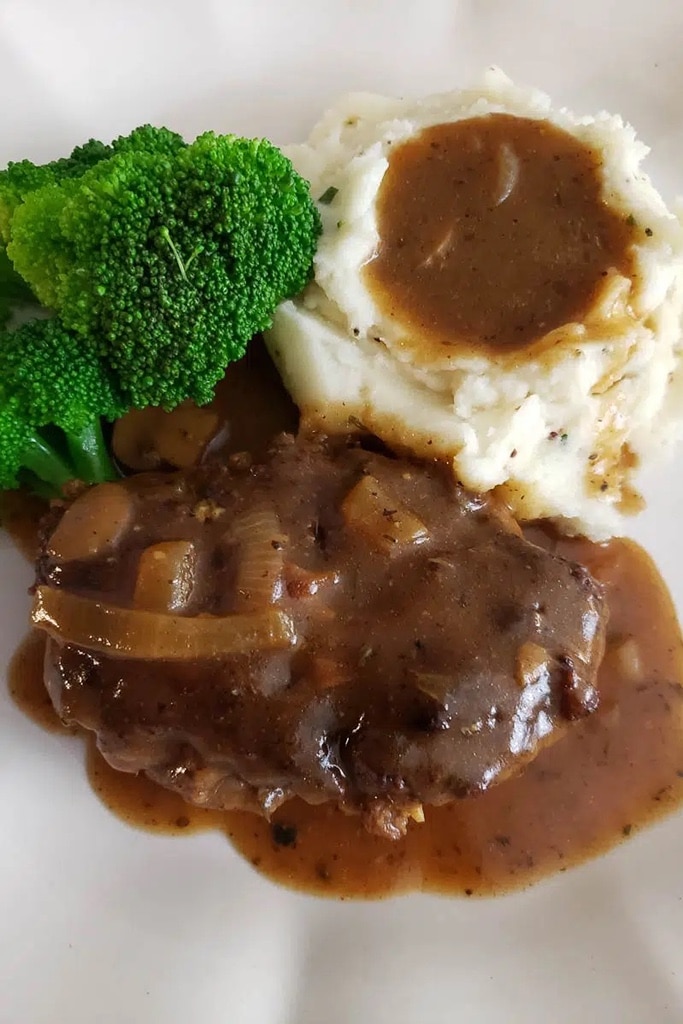 salisbury deer meat venison with mashed potatoes and gravy on top and broccoli 