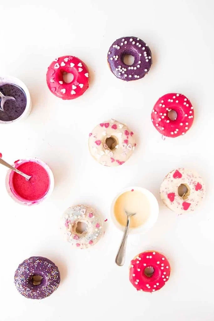 overhead view of assorted homemade valentines day donuts with small bowls of icing 