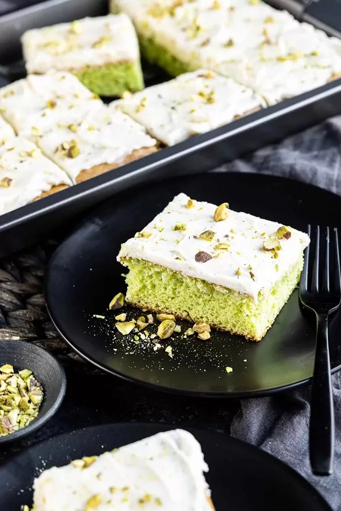 slice of pistachio cake on black plate with black fork 