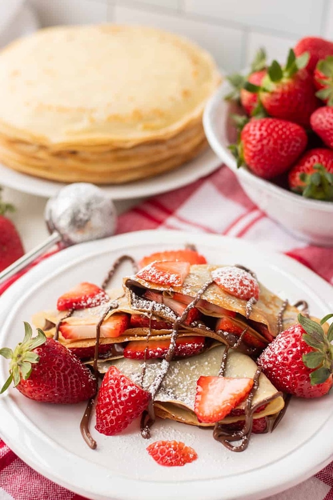 strawberry nutella crepes with chocolate drizzle and sliced strawberries 