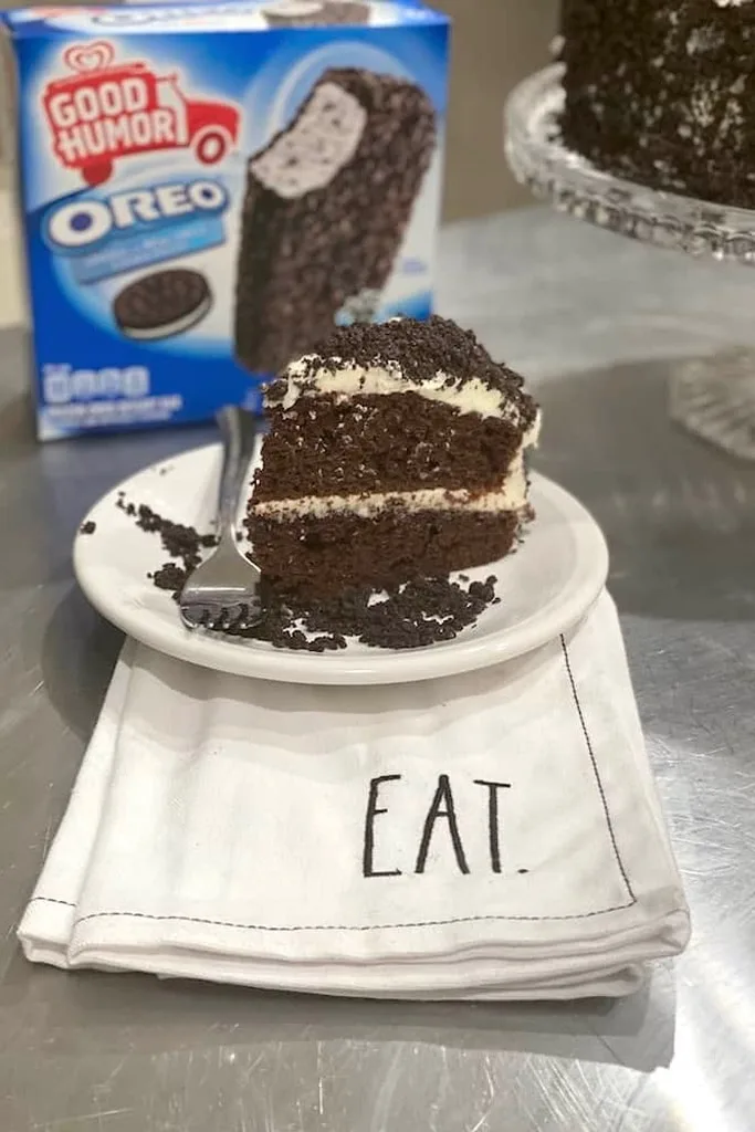 slice of cookies and cream Oreo cake on white plate with silver fork 