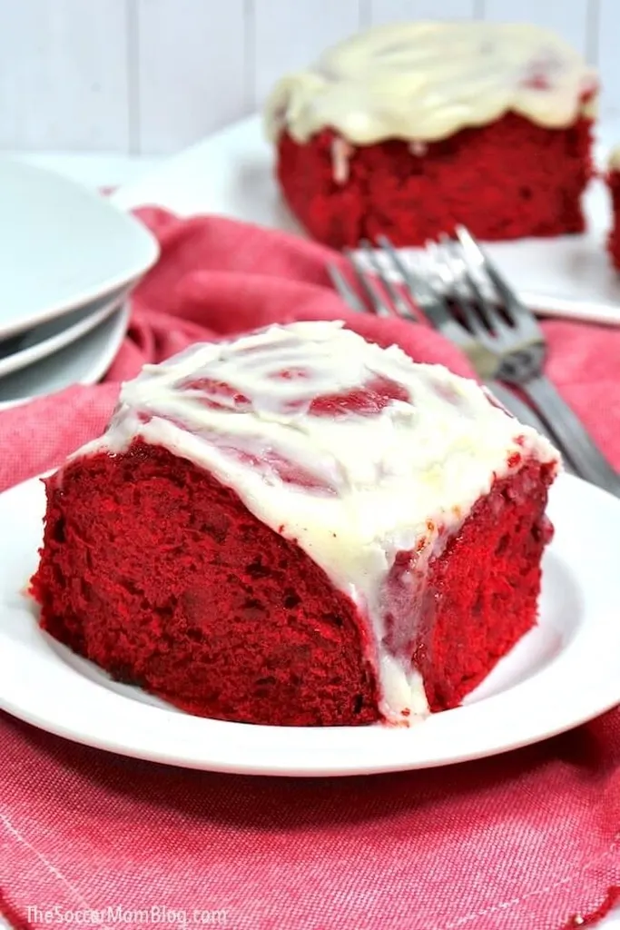 red velvet roll with icing on top on white plate 