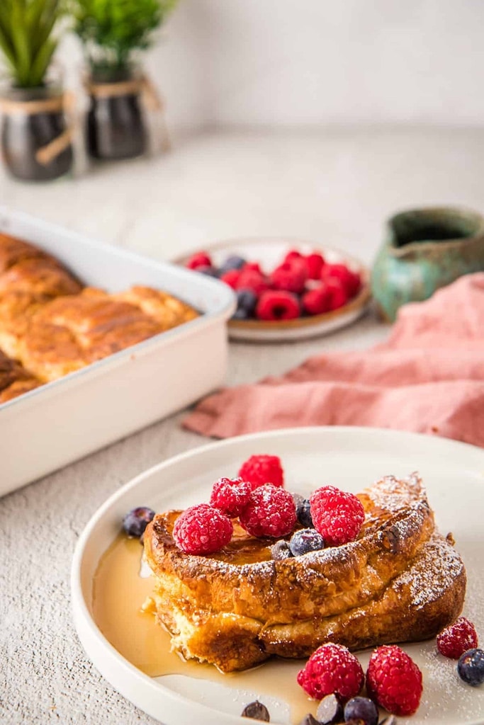 Croissant French Toast with syrup and berries on white plate 