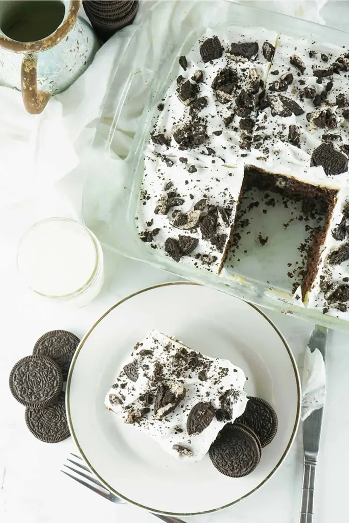 oreo poke cheesecake in glass casserole dish with slice on white plate 