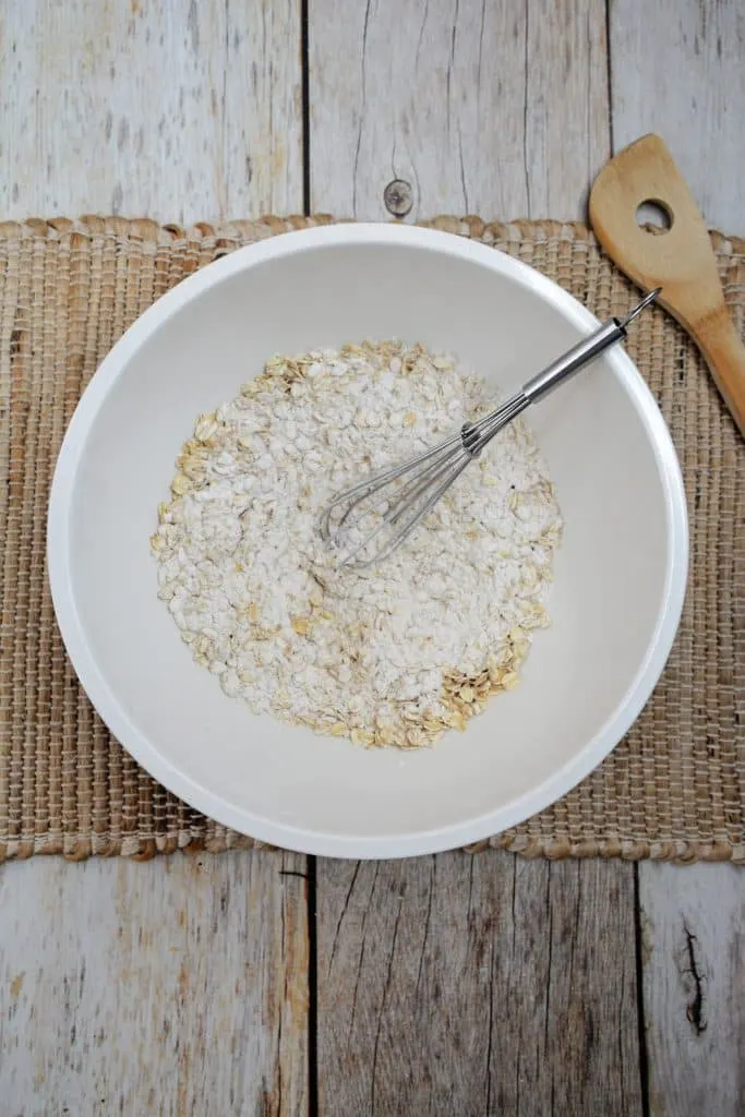 flour and rolled oats in white mixing brown with silver wisk