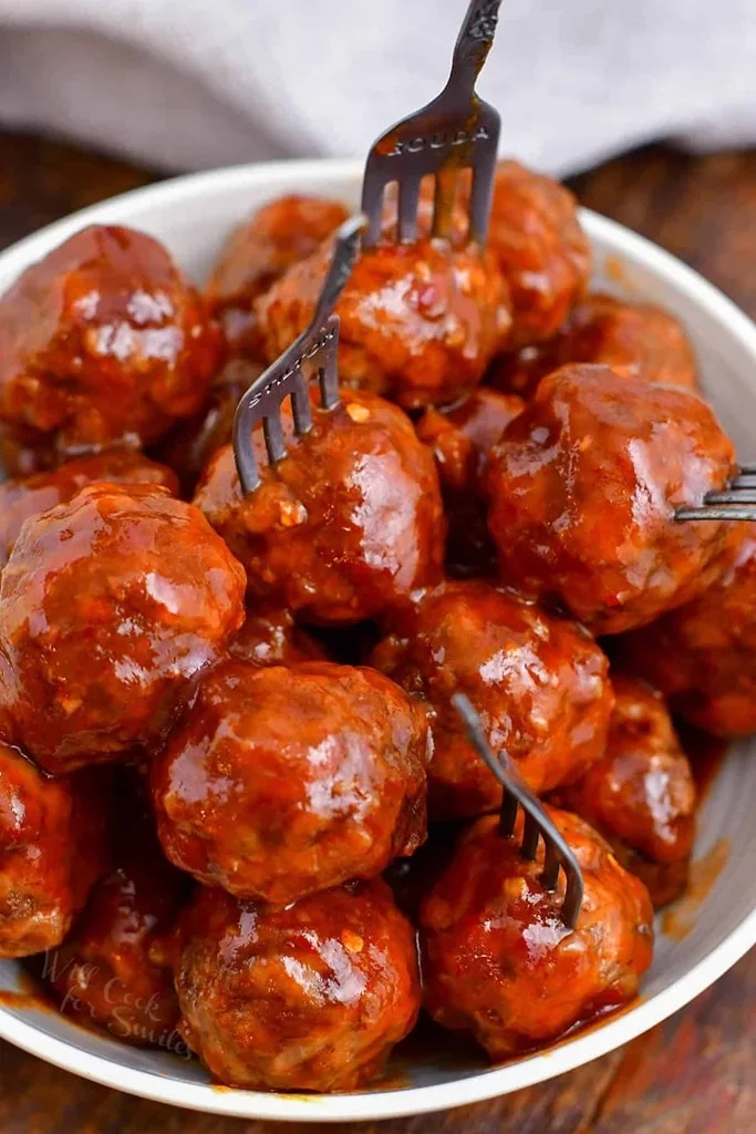 cocktail meatballs in white bowl with cocktail forks 