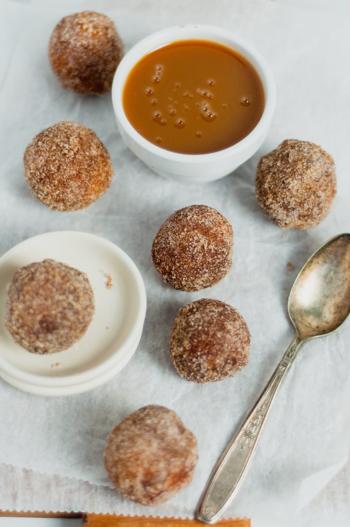 cinnamon sugar donut holes on parchment paper with spoon 