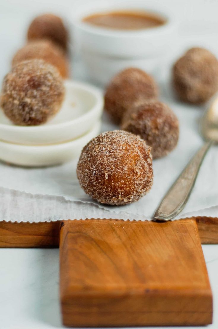 Cinnamon Sugar Donut Holes 34 close up of fried cinnamon sugar donut hole on parchment paper and wooden cutting board