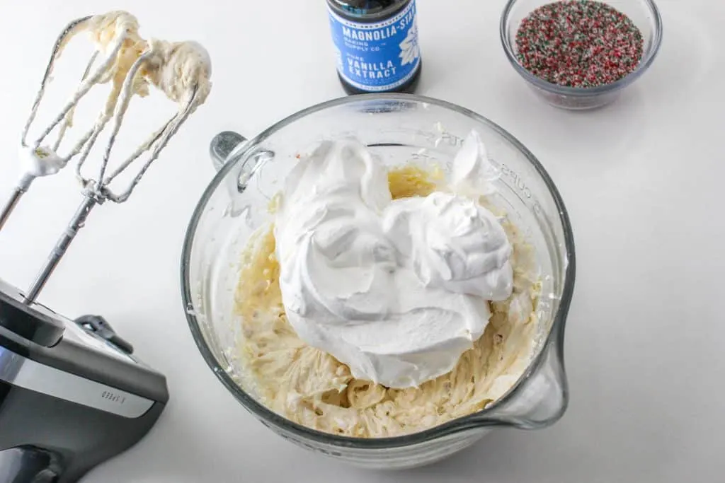 mixer beside of bowl of ingredients and whipped topping for christmas tree cake dip 