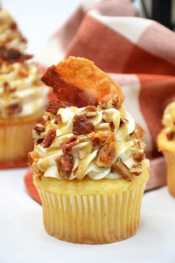 close up of maple bourbon cupcake with a piece of bacon on top