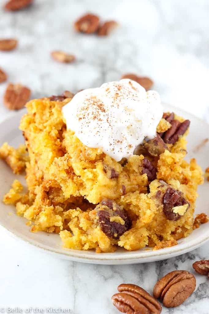 pumpkin dump cake topped with whipped cream on white plate 