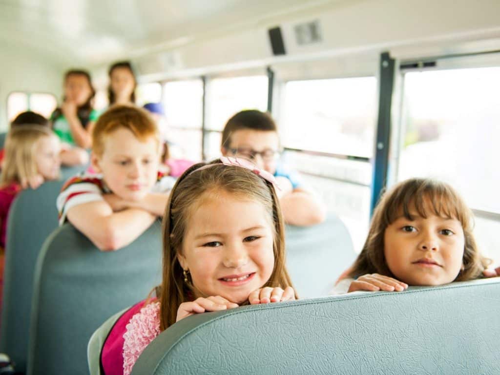Kids on school bus looking over the back of the seat 