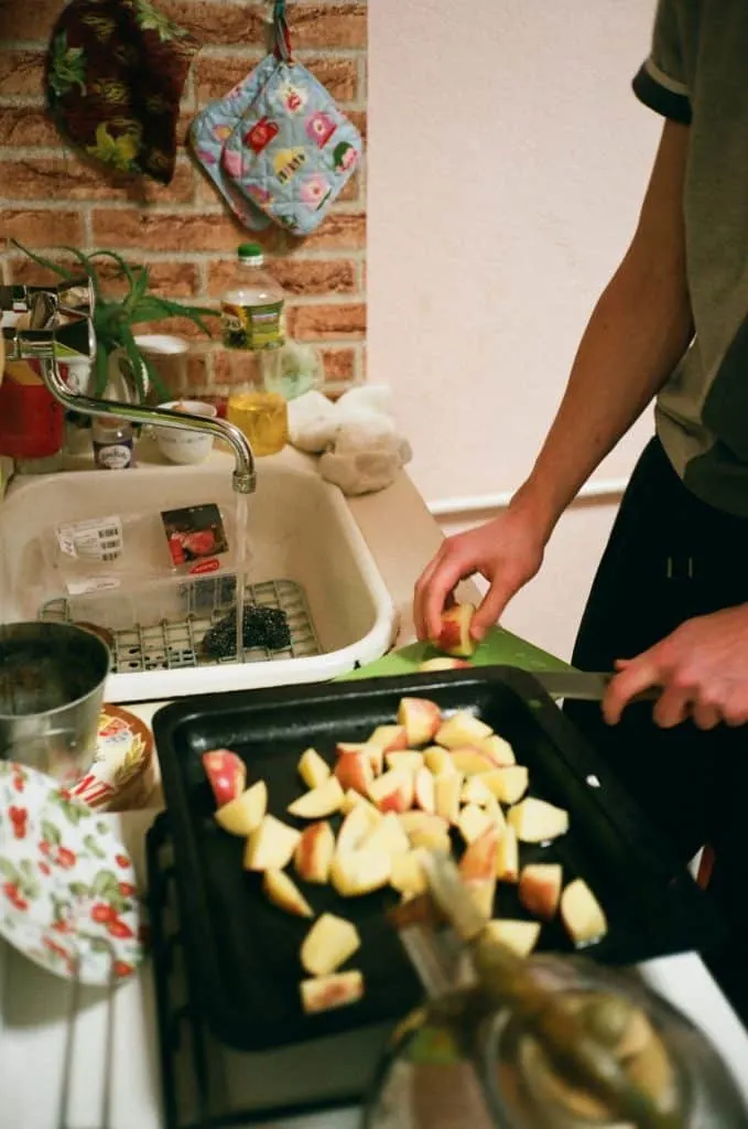 person dicing apples with apples on pan on countertop 
