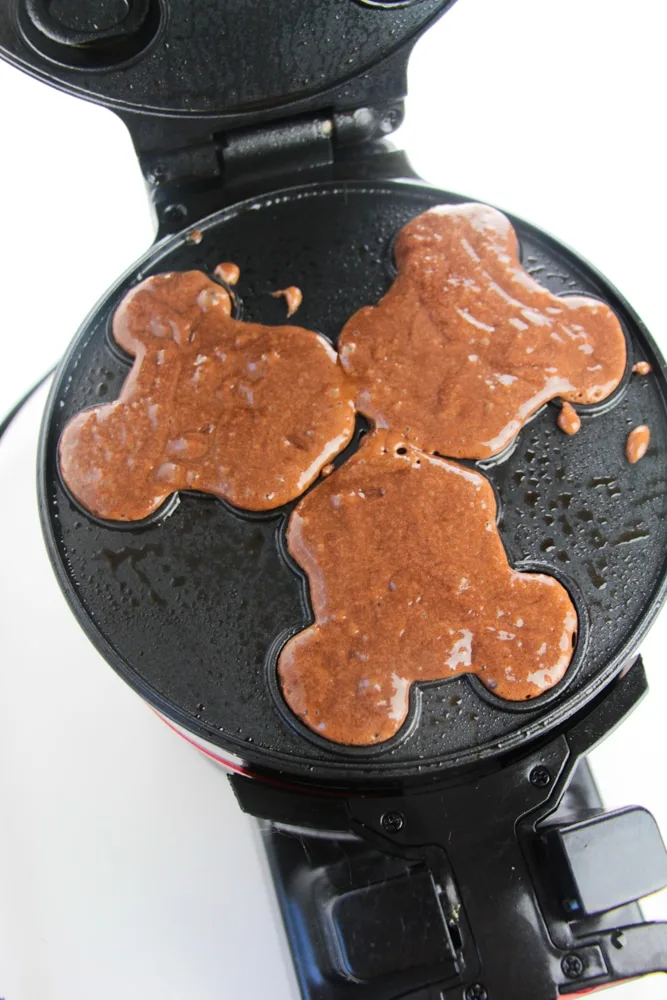 chocolate cake batter poured in Mickey Mouse waffle maker