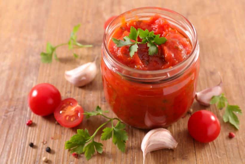 Slow Cooker Lasagna 3 spaghetti sauce in glass jar with tomatoes and garlic scatttered around