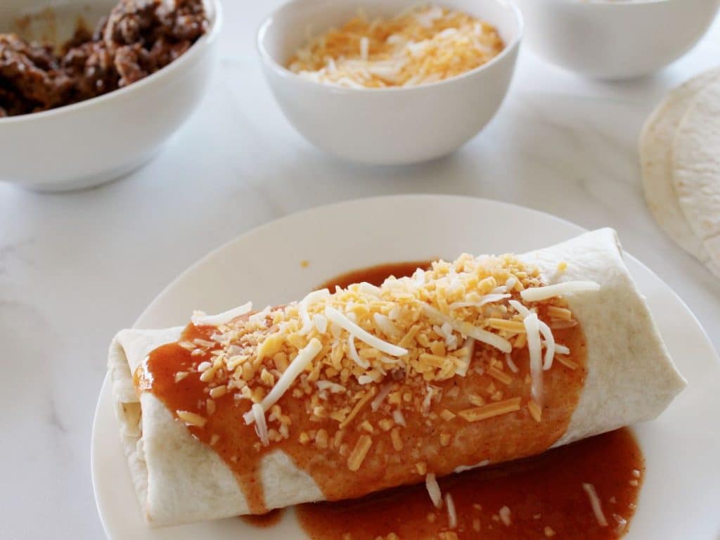 Taco Bell Enchrito Copycat Recipe 8 Rolled smothered Taco Bell copycat enchirito on a white plate