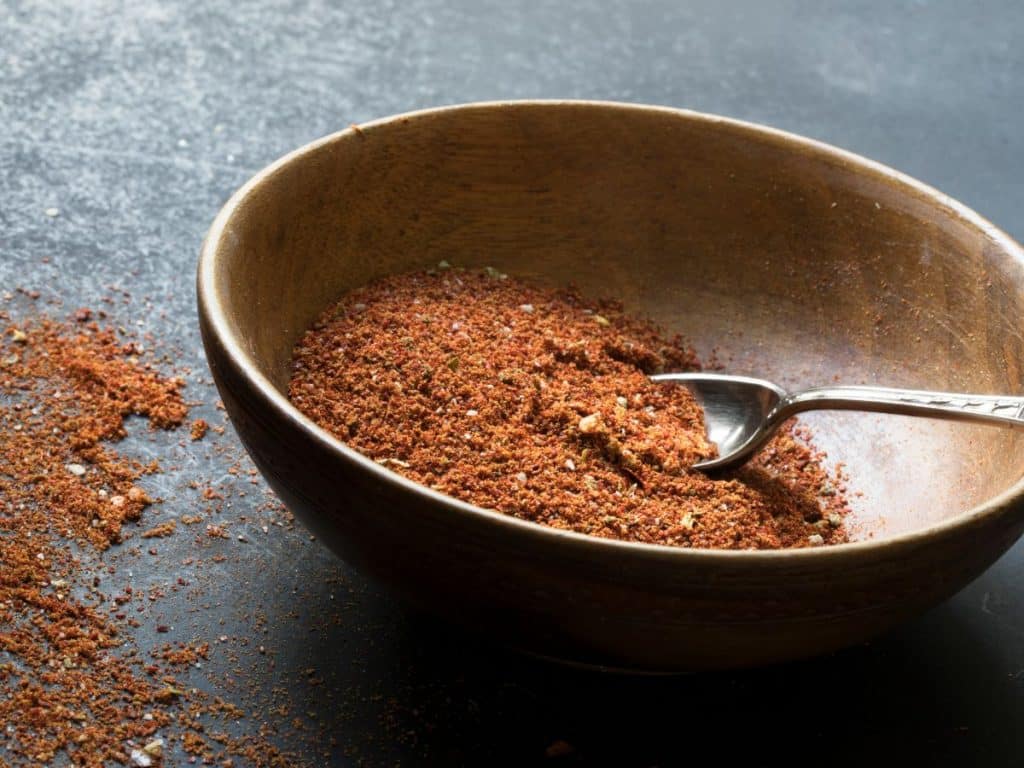 Cheesy Taco Casserole 4 homemade taco seasoning in a bowl with a spoon on a dark stone surface