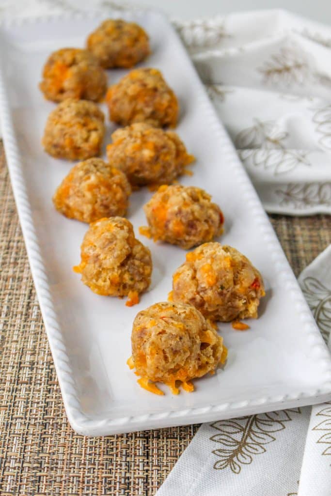 3 Ingredient Sausage Cheese Balls with Pimento Cheese 7 overhead view of Pimento Cheese Sausage Balls on white rectangle serving tray