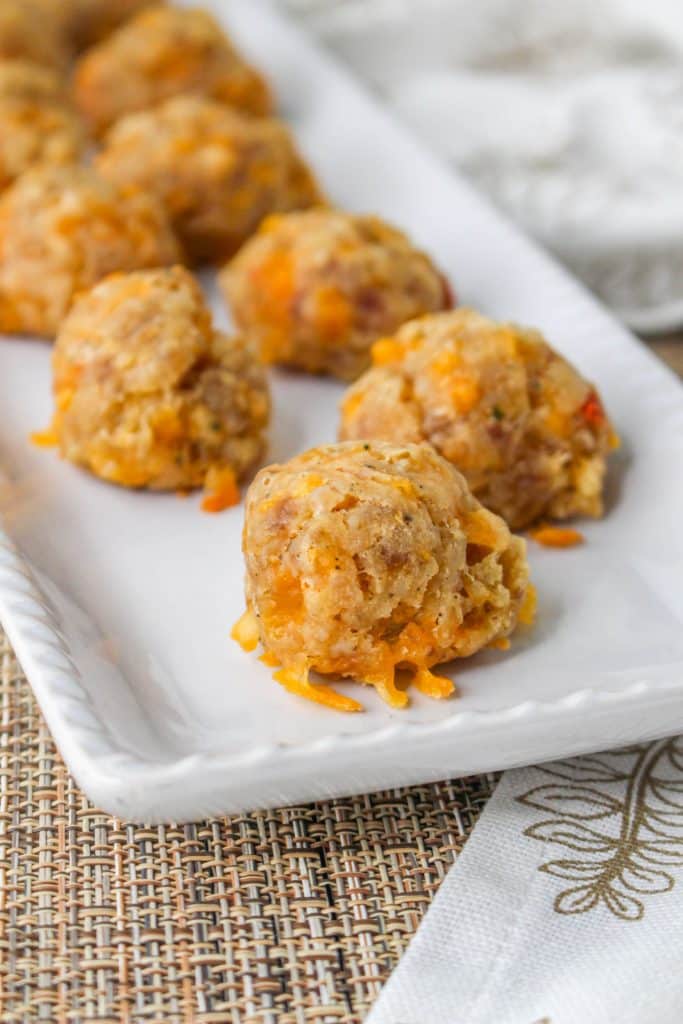 3 Ingredient Sausage Cheese Balls with Pimento Cheese 12 close up of Pimento Cheese Sausage Balls on white rectangle serving tray