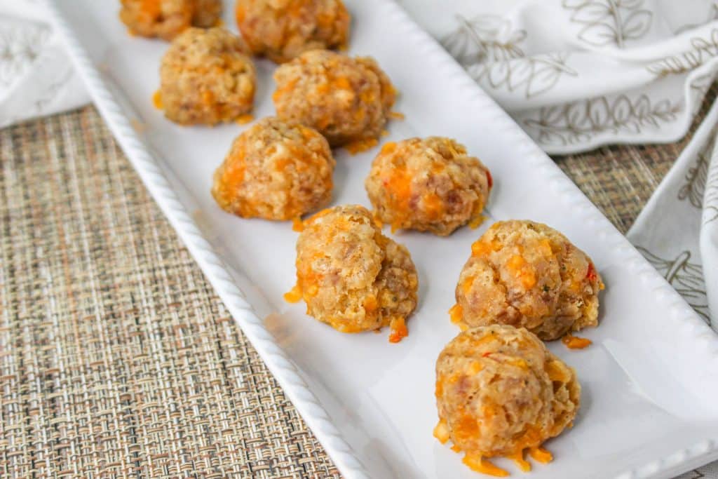 3 Ingredient Sausage Cheese Balls with Pimento Cheese 13 overhead view of Pimento Cheese Sausage Balls on white rectangle serving plate