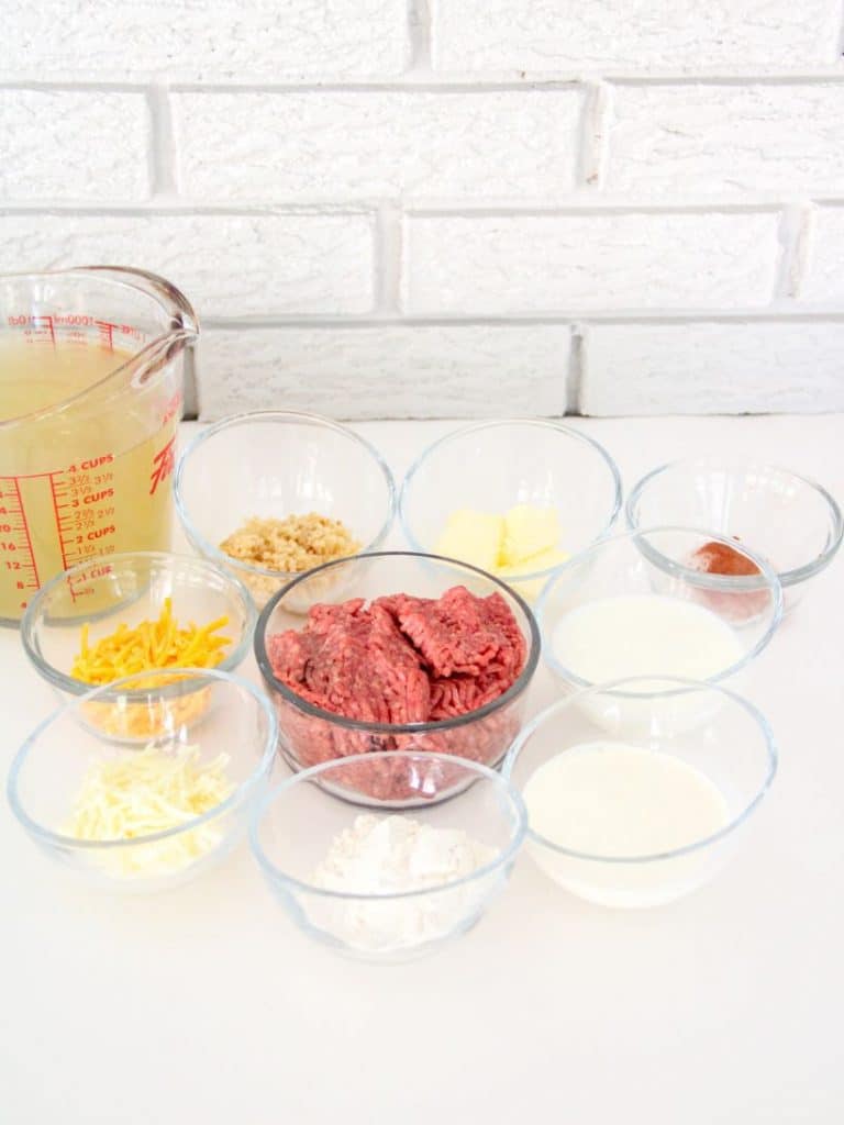 Sausage potato soup ingredients on small glass bowls on a white background.