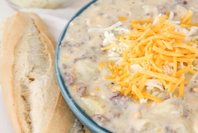 Sausage Potato Soup in Crockpot 5 Bowl of cheesy potato and sausage soup in a blue bowl with a loaf of bread next to it.