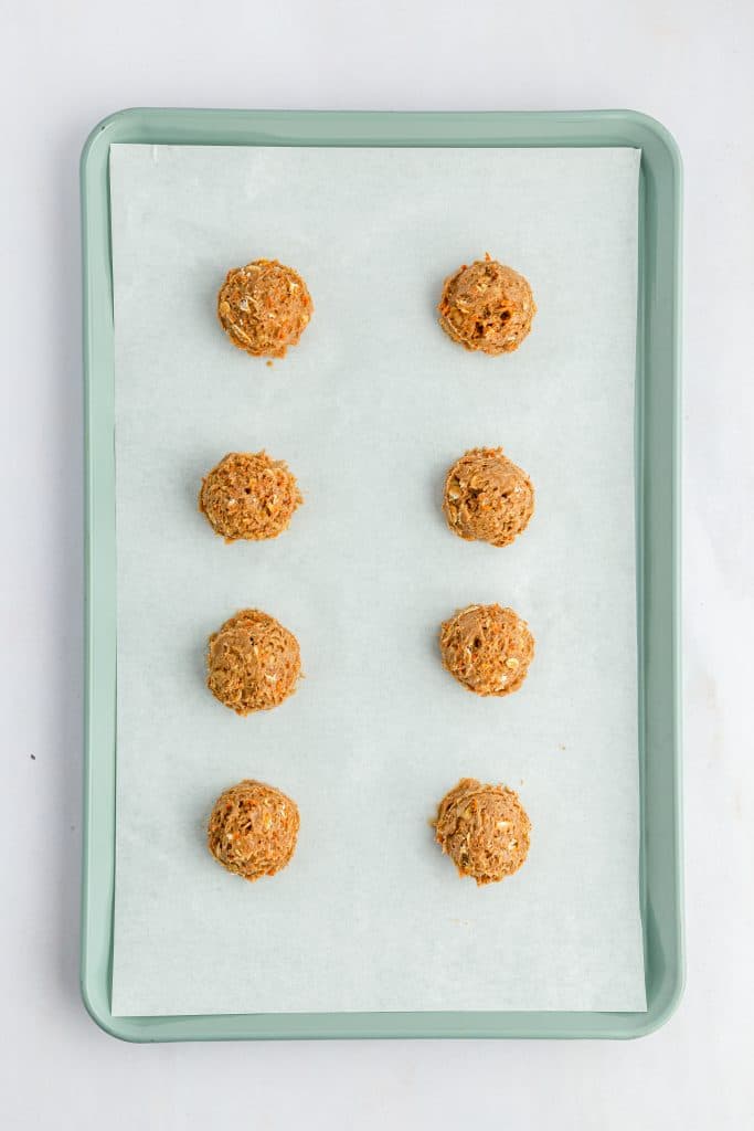 Carrot Cake Cookies 27 Uncooked carrot cake cookies on parchment paper covered blue baking sheet.