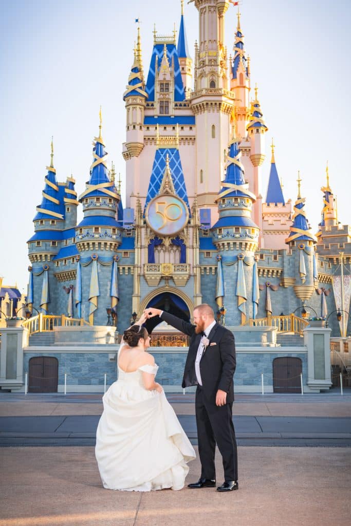 Everything You Need to Know About a Disney World Vow Renewal 38 bride and groom twirling in front of Cinderella's Castle in Disney World