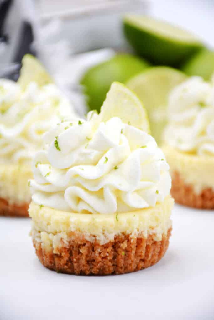 Mini Key Lime Cheesecakes 3 Key lime cheesecake bite with whipped cream on top.