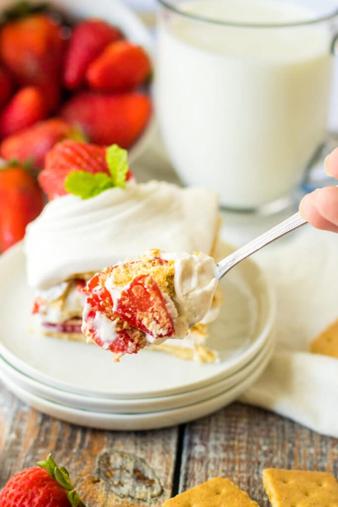 Easy Strawberry Icebox Cake 4 Strawberry ice box cake on white place with strawberries in background.