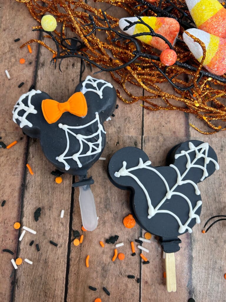 Disney Halloween Recipe (Mickey Oreo Pops) 11 overhead view of black halloween mickey Oreo pops with white webbing and orange Minnie bow