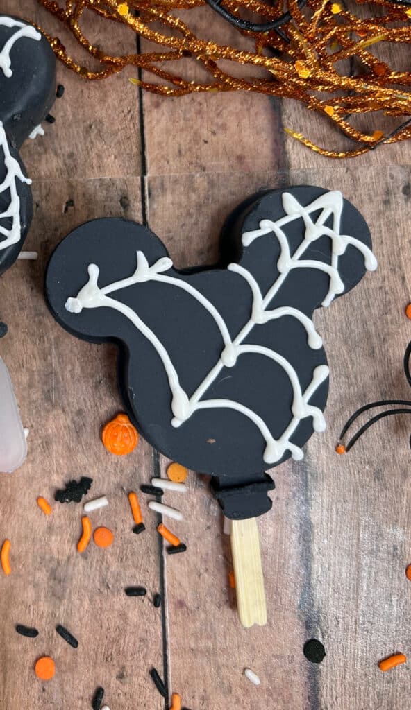 Disney Halloween Recipe (Mickey Oreo Pops) 6 up close view of black halloween Mickey Oreo pop with white webbing design