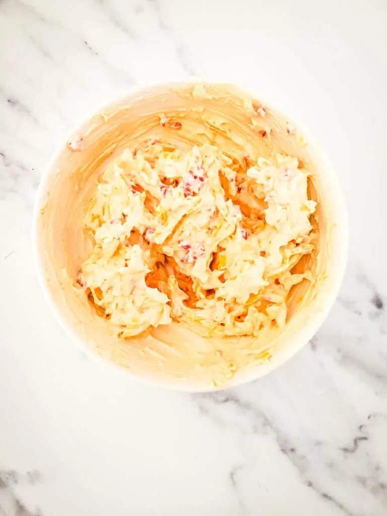 Pimento cheese mixture in a bowl on  a marble countertop.