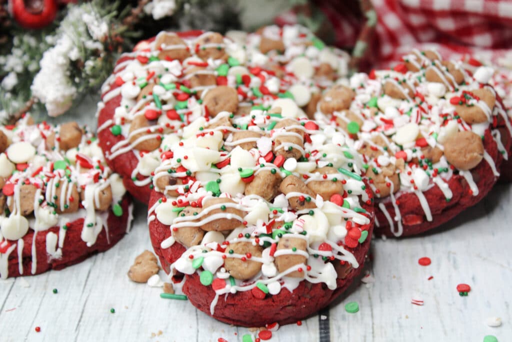 Santa's Cookies (Red Velvet Christmas Cookies) 8 Batch of Santa's cookies on a white wooden countertop with Christmas decorations in the background.