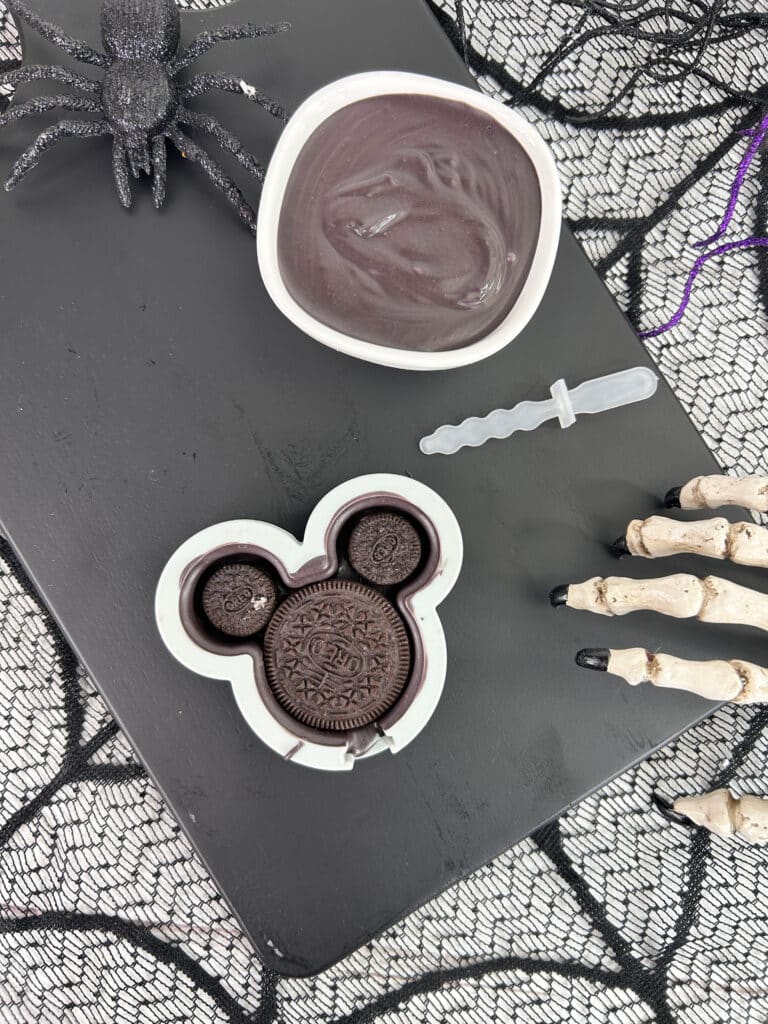 Disney Halloween Recipe (Mickey Oreo Pops) 5 overhead view of mickey mold with chocolate, melted chocolate and spider