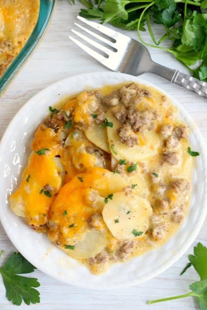 25 Venison Burger Casserole Recipes 25 Beef and potato casserole on a white plate with metal fork.