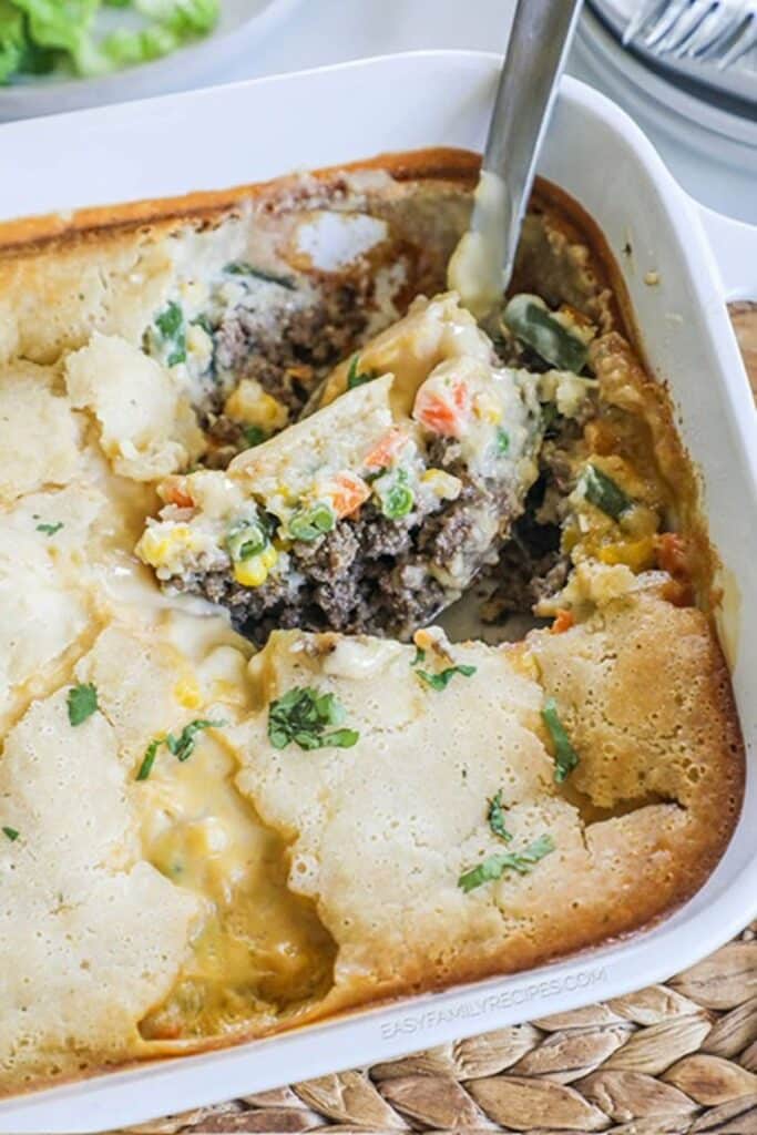 25 Venison Burger Casserole Recipes 26 Ground beef cobbler in a white casserole dish with metal spoon.