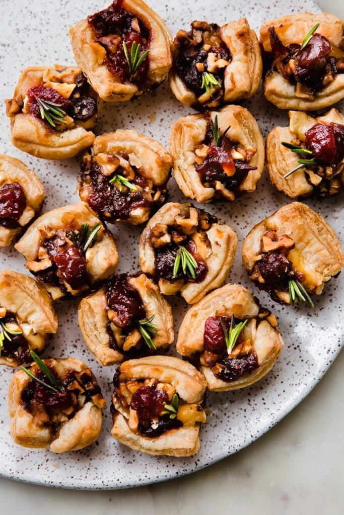 25 Christmas Appetizers That Travel Well 55 Cranberry brie bites on a white plate.
