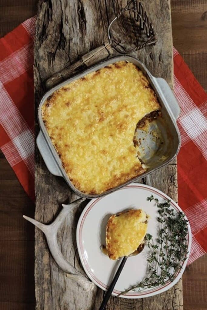 25 Venison Burger Casserole Recipes 15 Overhead view of Not Your Moms Shepherds Pie in a casserole dish, serving plate with shepherd's pie and a metal fork.