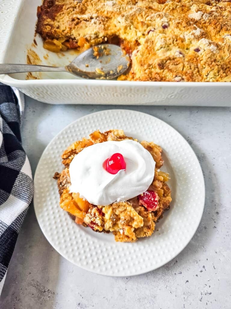 Pineapple Upside Down Dump Cake 2 overhead view of Pineapple Upside Down Dump Cake with whipped cream and cherry on top on white plate