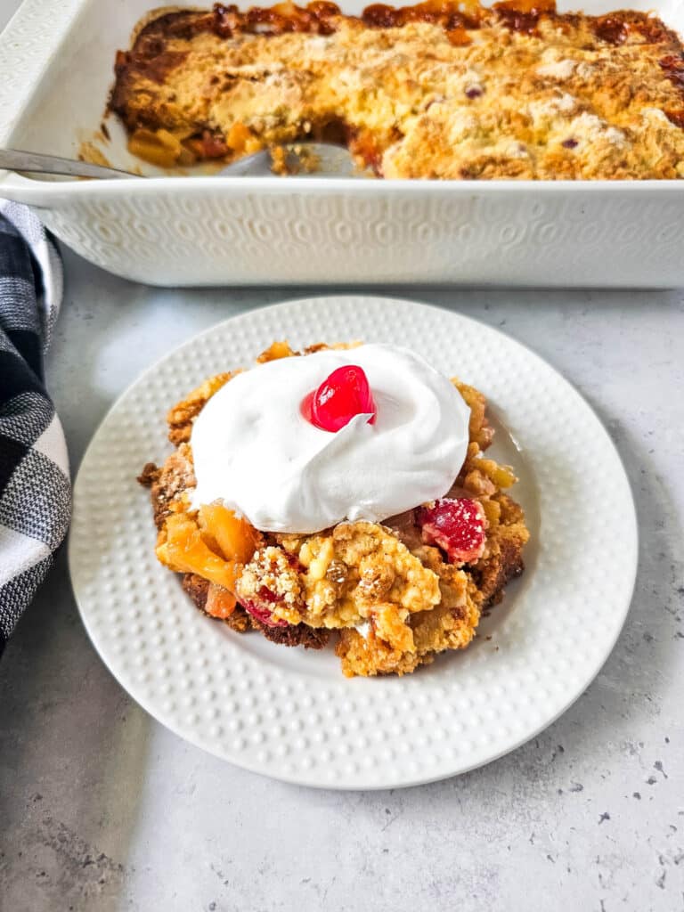 Pineapple Upside Down Dump Cake 12 overhead view of Pineapple Upside Down Dump Cake with whipped cream and cherry on top on white plate