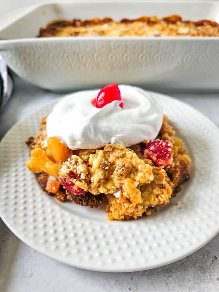 Pineapple Upside Down Dump Cake 13 overhead view of Pineapple Upside Down Dump Cake with whipped cream and cherry on top on white plate
