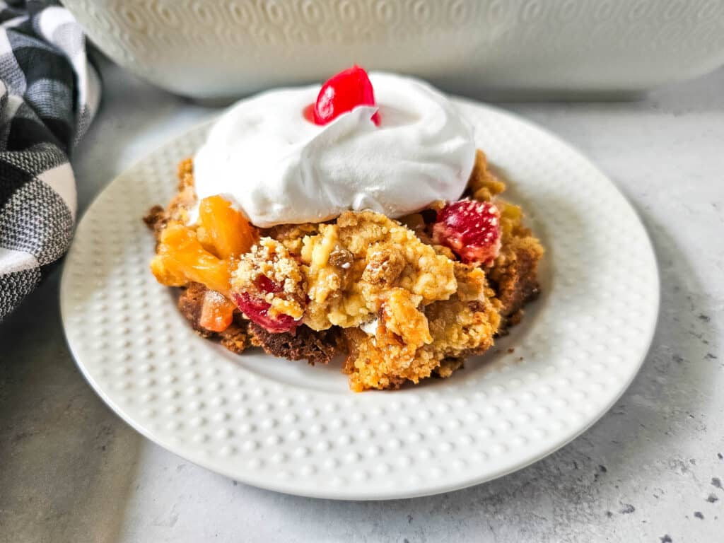 Pineapple Upside Down Dump Cake 10 overhead view of Pineapple Upside Down Dump Cake with whipped cream and cherry on top on white plate