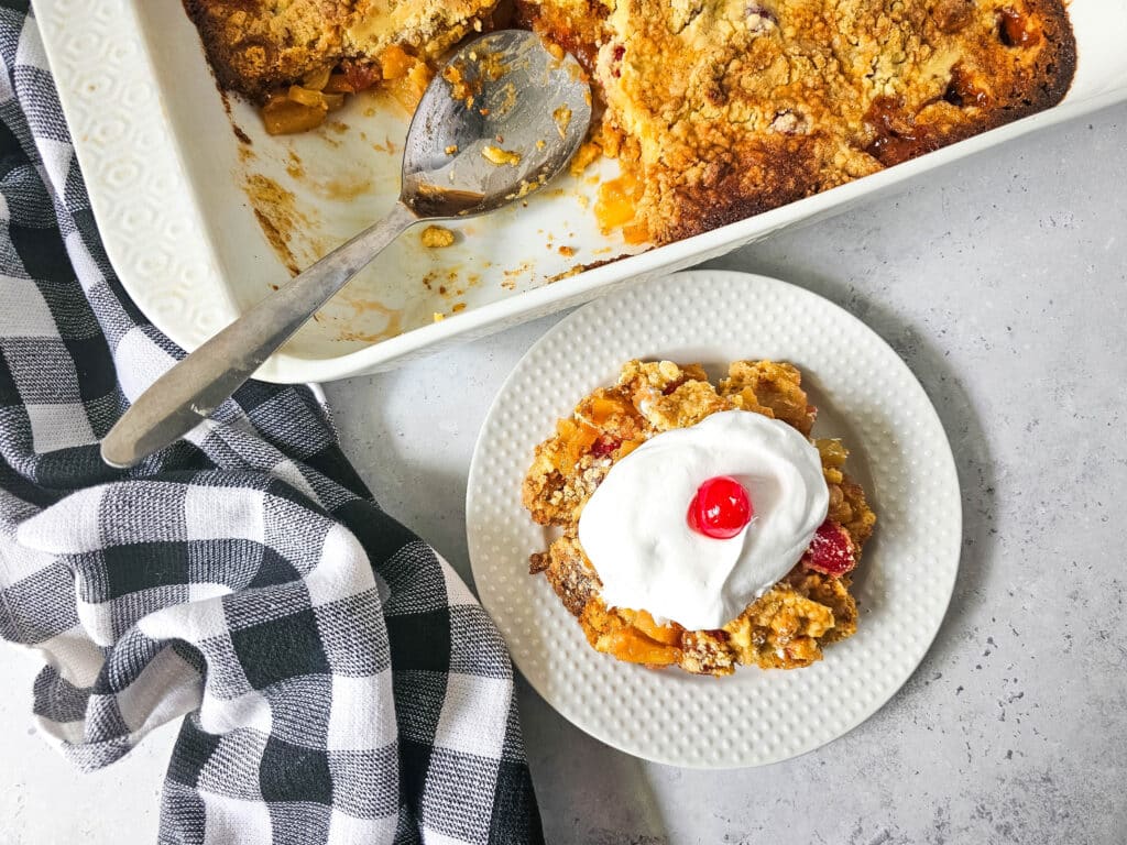 Pineapple Upside Down Dump Cake 9 overhead view of Pineapple Upside Down Dump Cake with whipped cream and cherry on top on white plate