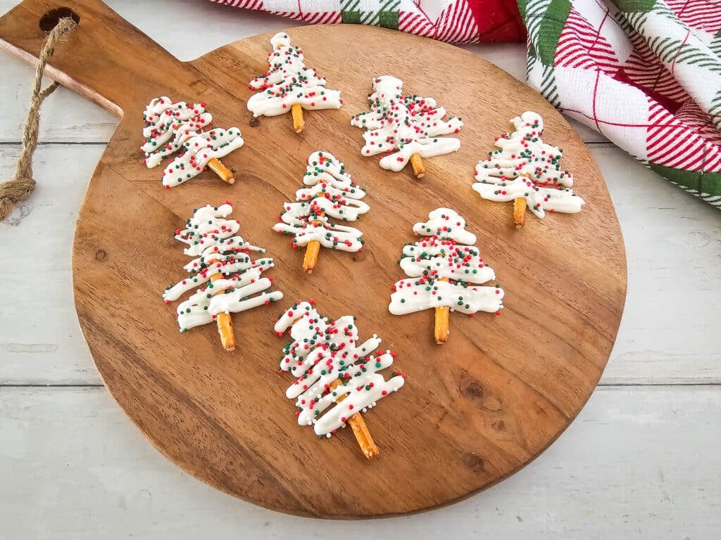 High angle shot of a round wooden board with Pretzel Christmas Trees on it.