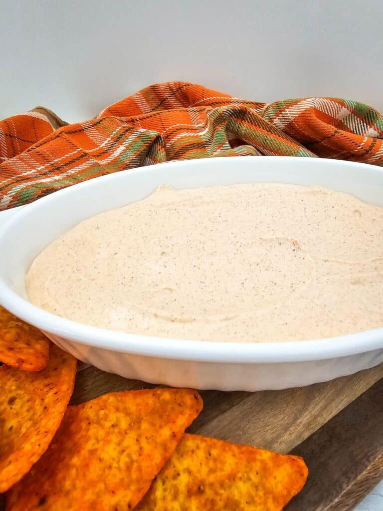 The finished 2-ingredient Taco Dip in a white, oval dish, surrounded by Doritos.