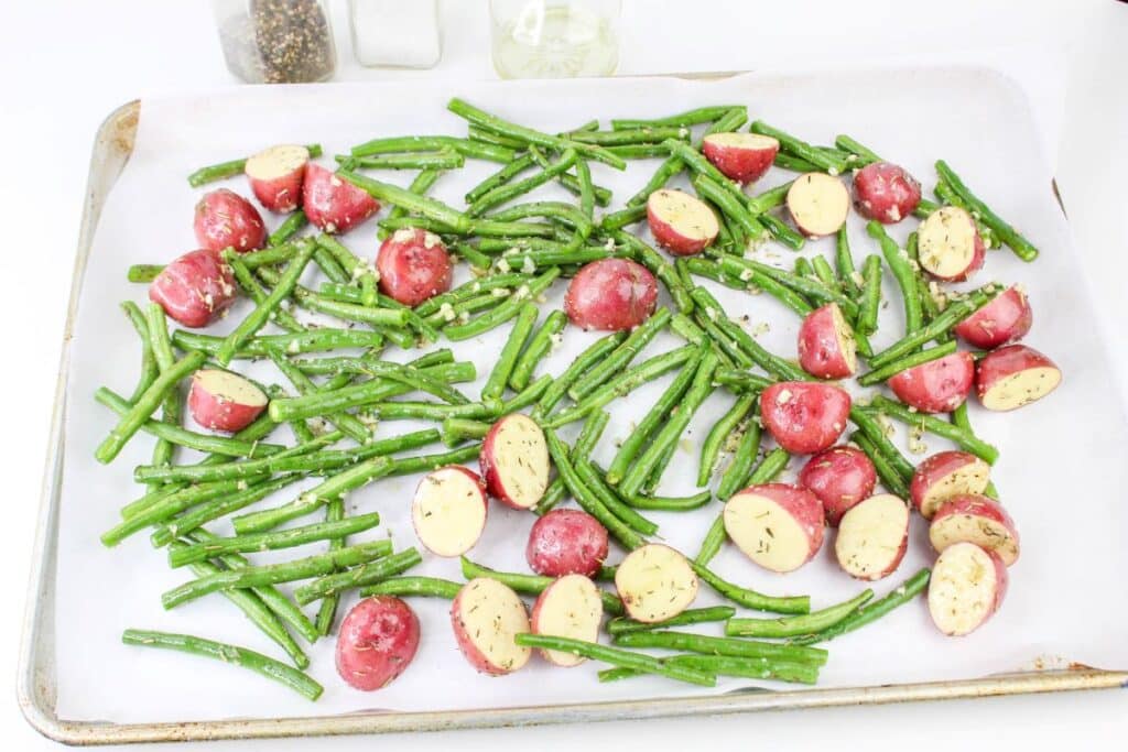 Leftover Roasted Potatoes and Green Beans 7 Seasoned potatoes and green beans spread evenly on a sheet tray with parchment paper in it.